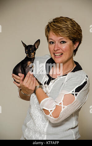 Dame mit Hund Lilly eine Tasse Tee Chihuahua/Pincher Stockfoto