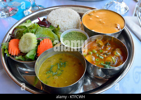 Platte von Lamm Tikka Masala, mit aaloo Mattar, Linsen, Reis, Naan serviert und Salat. Stockfoto