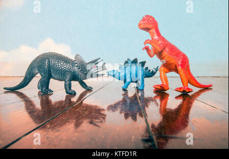 Drei Dinosaurier Spielzeug auf einer alten hölzernen Flor mit Reflexion Stockfoto