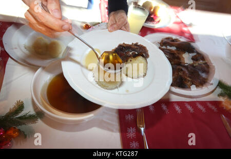 Kaufbeuren, Deutschland. 25 Dez, 2017. Eine Frau giesst Soße über Stücke von gänsebraten und knoedel (Knödel) auf einem festlich geschmückten Tisch in Kaufbeuren, Deutschland, 25. Dezember 2017. Foto: Karl-Josef Hildenbrand/dpa/Alamy leben Nachrichten Stockfoto