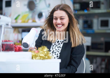 Haircare. Schöne lange behaarte Frau trocknen Haar in elektronischen Speichern Stockfoto