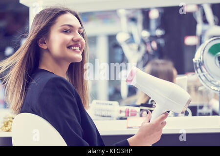 Haircare. Schöne lange behaarte Frau trocknen Haar in elektronischen Speichern Stockfoto