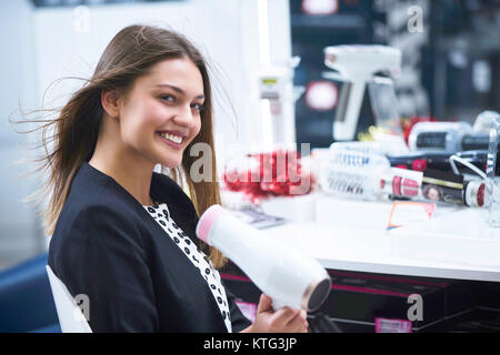 Haircare. Schöne lange behaarte Frau trocknen Haar in elektronischen Speichern Stockfoto