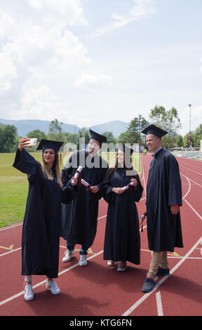 Bildung, Graduierung und Personen Konzept - Gruppe von Happy internationale Studierende in Mörtel Boards und Bachelor- Kleider mit den Diplomen Stockfoto