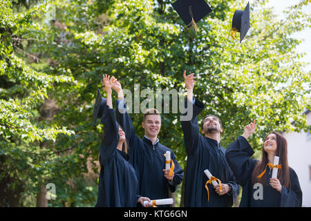 Bildung, Graduierung und Personen Konzept - Gruppe von Happy internationale Studierende in Mörtel Boards und Bachelor- Kleider mit den Diplomen Stockfoto