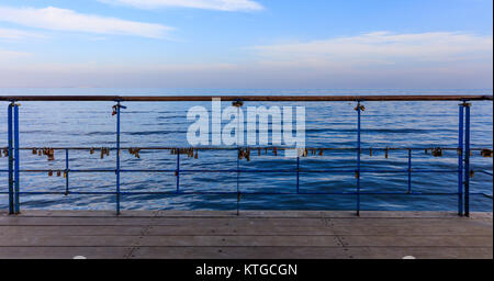 Rusty Vorhängeschlösser geschlossen auf geschälte Geländer beweisen Liebe. Nahaufnahme, blauer Himmel und Meer Kulisse. Stockfoto