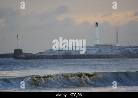 Winter Storm Hits Land am Hafen Aberdeen. Wellen und Gürtel Ness Leuchtturm im Hintergrund. Schottland, Großbritannien. Dezember 2017. Stockfoto