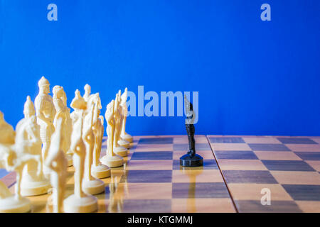 Schach auf schwarzen Hintergrund. Eine schwarze Bauer steht vor einer feindlichen Armee Stockfoto