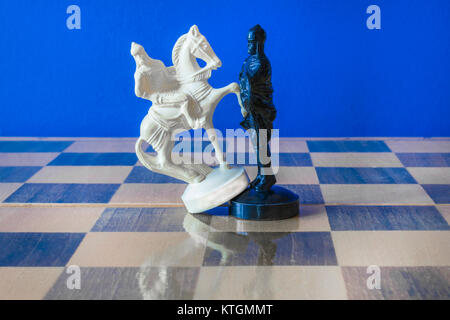 Schach auf schwarzen Hintergrund. White Horse steht vor Bauer Stockfoto