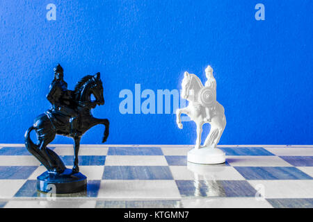 Schach auf schwarzen Hintergrund. White Horse steht vor einem schwarzen Pferd Stockfoto