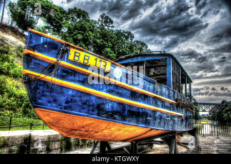 High Dynamic Range Foto des blauen Holzboot mit Gelb unten an bewölkten Tag in Lockport lock in Lockport, New York Niagara County Stockfoto