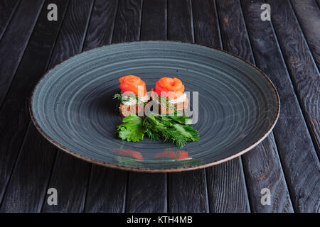 Vorspeise für den Empfang. Geräucherter Lachs mit Ricotta und Dill auf Stück Schwarzbrot Stockfoto