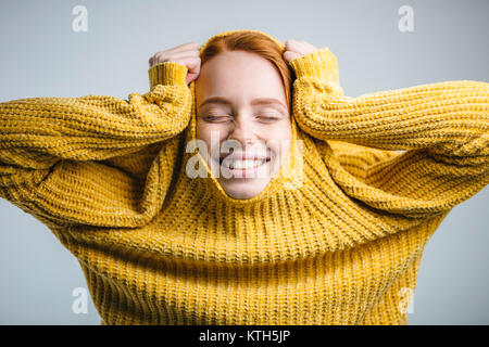 Mode junge Frau zieht gelb Pullover und Spaß auf weißem Hintergrund Stockfoto