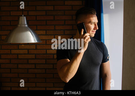 Der Mensch am Telefon sprechen im Haus in der Nähe von Fenster Stockfoto