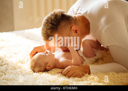 Vater liegt auf dem Bett und hält sein Baby Stockfoto