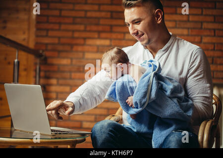 Vater mit Neugeborenen Arbeiten von zu Hause mit Laptop Stockfoto