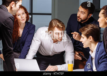 Lächelnd weibliche und männliche Kollegen am Tisch sitzen, am Laptop Suchen Stockfoto