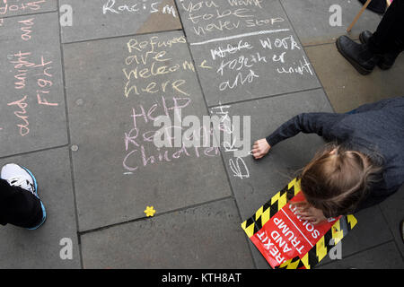 "Flüchtlinge sind willkommen hier" und "Helfen Flüchtlingskindern" Meldungen sind auf dem Bürgersteig durch Kinder gegen Rassismus, London, UK protestieren geschrieben. Stockfoto