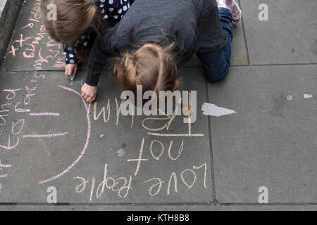 Kleine Mädchen, Schwestern Honig und Bluebelle, Schreiben anti-Trump und anti-Rassismus Nachrichten auf dem Bürgersteig während der UN-Anti-Rassismus Tag in London, Großbritannien Stockfoto