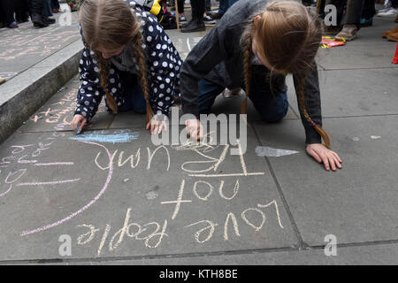 Kleine Mädchen, Schwestern Honig und Bluebelle, Schreiben anti-Trump und anti-Rassismus Nachrichten auf dem Bürgersteig während der UN-Anti-Rassismus Tag in London, Großbritannien Stockfoto