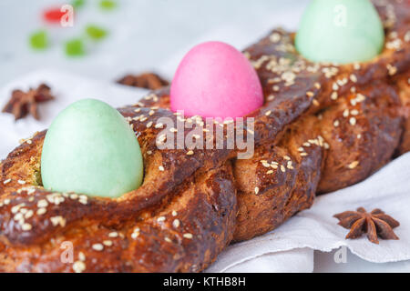 Traditionelle griechische Ostern Brot - tsoureki in Ostern Dekorationen mit bemalten Eiern und Blumen. Ostern Festival Konzept. Stockfoto