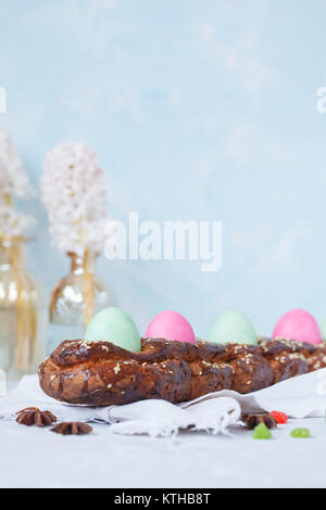 Traditionelle griechische Ostern Brot - tsoureki in Ostern Dekorationen mit bemalten Eiern und Blumen. Ostern Festival Konzept. Stockfoto