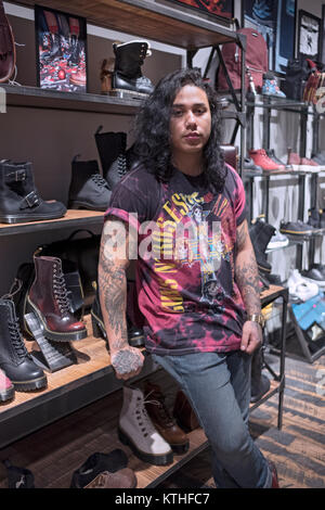 Eine junge männliche Verkäufer mit langen Haaren am Dr. Martens Store im Queens Center Shopping Mall in Elmhurst, Queens, New York City. Stockfoto