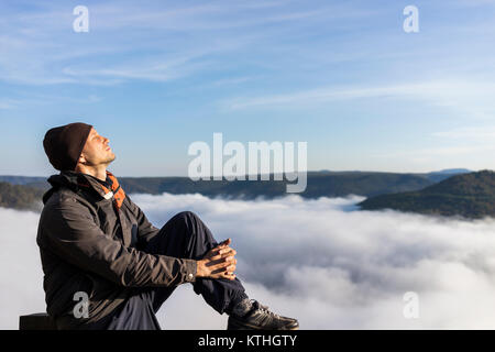 Mann von Bergen und Nebel Wolken Tal im morgendlichen Sonnenaufgang in Grandview übersehen, West Virginia sitzen Stockfoto