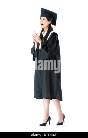 Gerne fröhliche weibliche Student Absolvent Wandern auf weißem Hintergrund und mit Mobile Smartphone Suchen Arbeitsplatz planen. Stockfoto