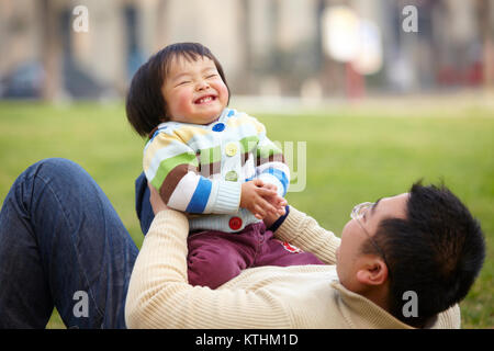 Gerne asiatische Vater spielt mit seinem kleinen Mädchen Outdoor im Park Stockfoto