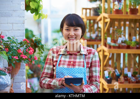 Eine schöne chinesische Frau Arbeiten in das Lächeln des Floristen an Kamera Stockfoto