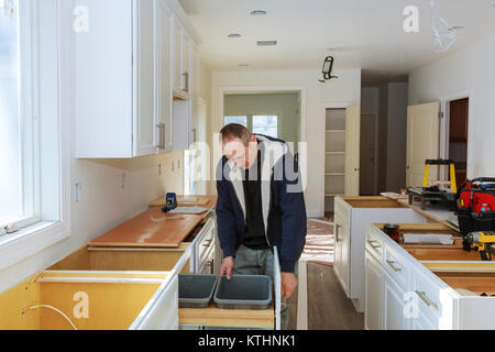 Der Arbeitnehmer setzt auf dem weißen Gehäuse mit einem Schraubendreher einbauen Küchenschränke Stockfoto