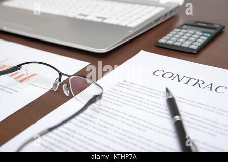 Business Konzepte mit Vertrag, Notebook, Brille, Rechner, und Graphen auf dem Schreibtisch Stockfoto