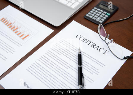 Business Konzepte mit Vertrag, Notebook, Brille, Rechner, und Graphen auf dem Schreibtisch Stockfoto