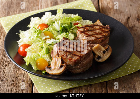 Gesunde Ernährung: Filet mignon Steak mit Pilzen und frisches Gemüse Salat close-up auf einem Teller. Horizontale Stockfoto