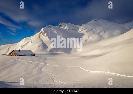 Am frühen Morgen Sonne durch über eine fantastische Berglandschaft bedeckt mit viel frischem Schnee zu brechen. Links im Bild der 'Chlushütte' ist s Stockfoto