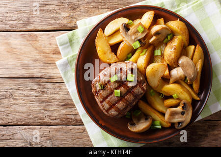 Gegrilltes Filet Mignon mit Kartoffeln und Pilzen close-up auf einem Teller. horizontal oben Ansicht von oben Stockfoto