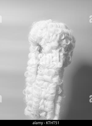 Perücke auf einem grauen Hintergrund beurteilen. Stockfoto