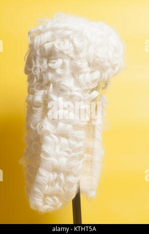 Perücke auf gelbem Hintergrund beurteilen. Stockfoto