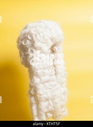 Perücke auf gelbem Hintergrund beurteilen. Stockfoto