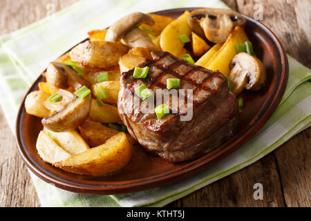 Filet Mignon mit gebratenen Kartoffeln und Pilzen close-up auf einem Teller auf dem Tisch. Horizontale Stockfoto