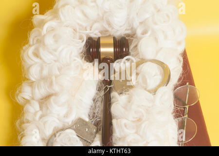 Für Richter: Richter Perücke, handcluffs, Richter Hammer, Buch Ende Brillen auf gelbem Hintergrund Stockfoto