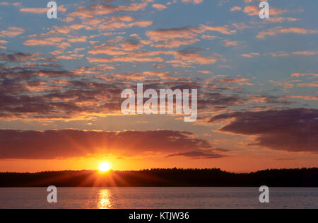 Sonnenuntergang über dem Meer. Reflexion des Sonnenlichts in den Meereswellen. Roter Himmel in den Strahlen des Sonnenuntergangs. Stockfoto