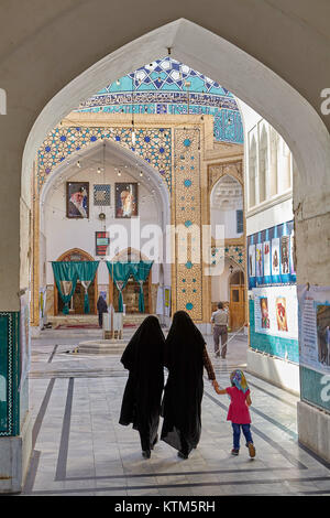 Yazd, Iran - 22. April 2017: Zwei muslimische Frauen, in Schwarz islamische Schleier, mit einem Mädchen in einem rosa Kleid und Kopftuch, am Eingang zur Moschee. Stockfoto