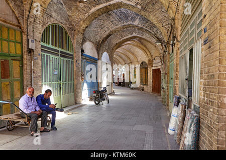 Yazd, Iran - 22. April 2017: Zwei Männer sitzen auf einer Katze in den gewölbten Durchgang der orientalischen Basar. Stockfoto