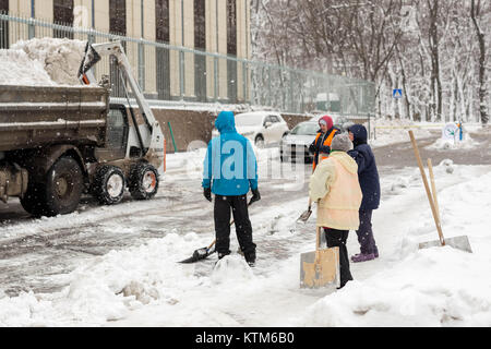 Kiew, Ukraine - 21. Dezember 2017: Arbeiter reinigt Gehweg im Appartment Bauhof während der schweren Schneefälle Stockfoto