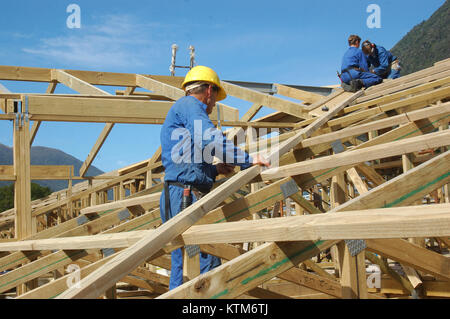 Bauarbeiter arbeiten auf dem Dach eines großen Hauses Stockfoto