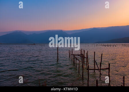 Sonnenuntergang am See mit den Überresten einer hölzernen Pier unter freien Himmel Stockfoto