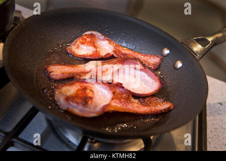 In der Pfanne gebratener Speck auf den Herd Stockfoto