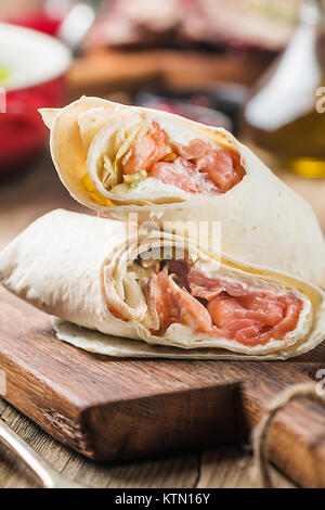 Frische Tortilla Wrap mit Gemüse und Lachs auf Holz Schneidebrett Stockfoto